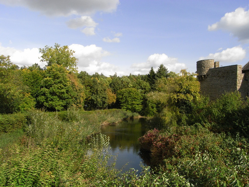 Wassergraben mit Burg im Hintergrund